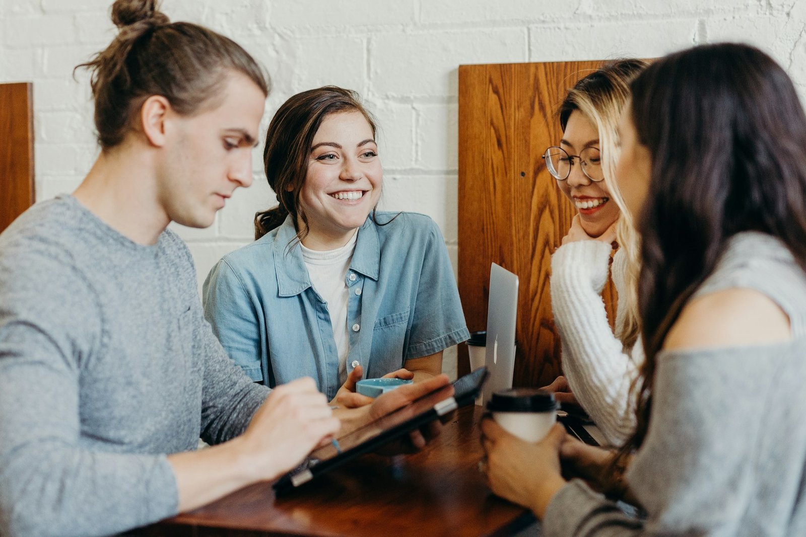 Jovens conversando e sorrindo ao redor de uma mesa.